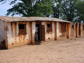 the kitchen is a rust streaked single storey building with a very uneven corrugated iron roof