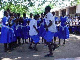 children at Jarreng in blue uniforms - the boys dance while the girls look on and clap