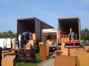 9am - two container trucks and a smaller van being loaded with furniture in the open air