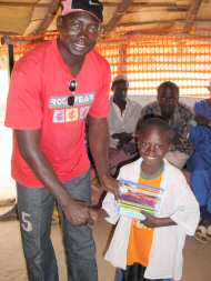 Kemo giving a pencil case to a newly sponsored child