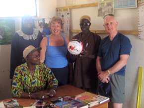 a signed football and the Mr Majeika books presented to the Headteacher, Mr Sima (seated)