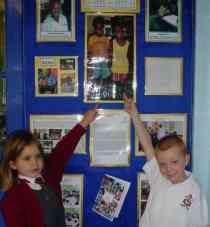 two children point to a picture of Abdoulrahman and Yusupha on the school notice board