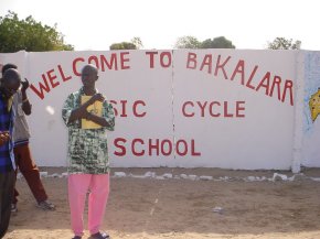 the wall is covered in paintings - this panle has the message 'Welcome to Bakalarr Baisc Cyle School'