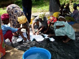 Busumbala women work on a large piece of fabric to prepare it for dying